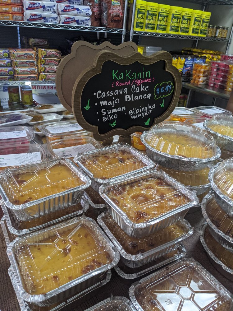 Trays of golden cassava cake under a chalkboard sign listing cassava cake, maja blanca and other kakanin