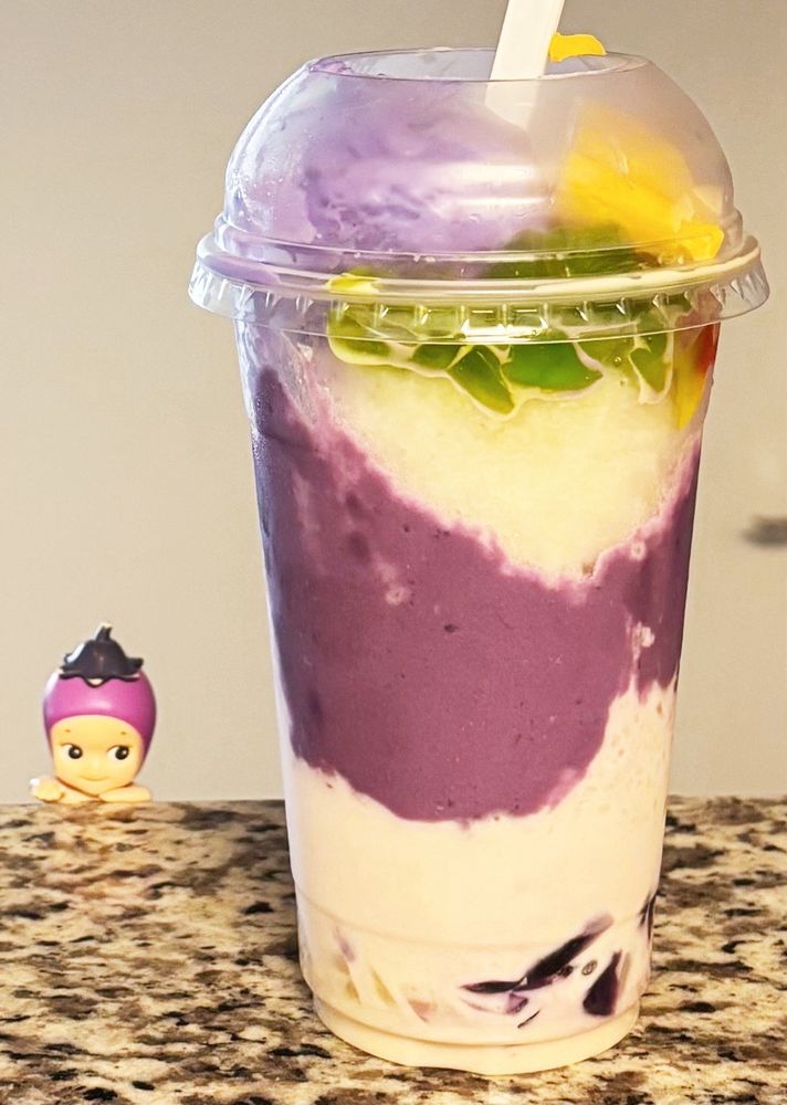 A tall cup of halo-halo with ube ice cream, purple ube swirls and colorful toppings
