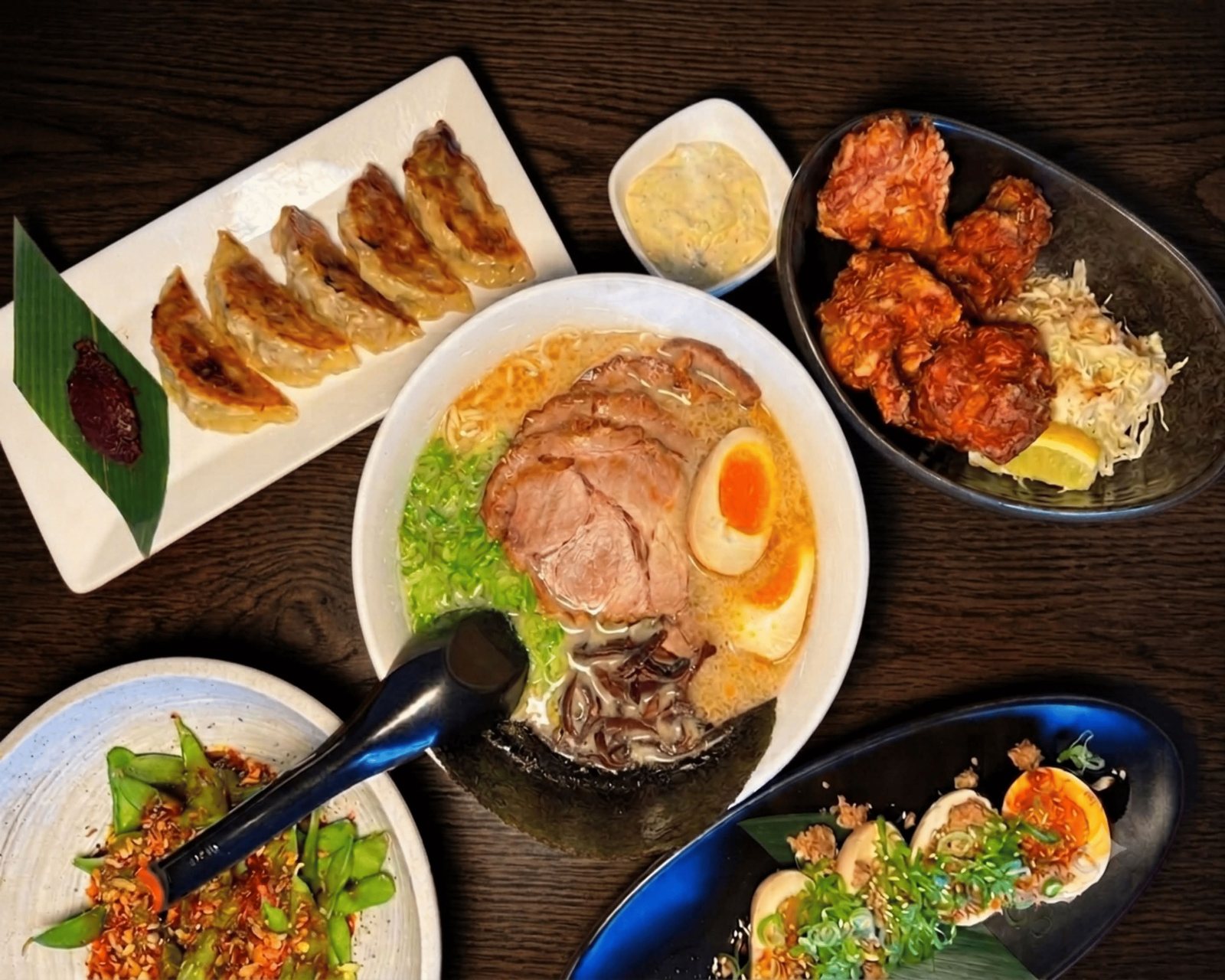 Ramen bowls with gyoza and karaage on a dark table